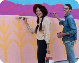 Young girl and guy painting a mural