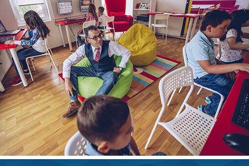 Teacher siting on a bean bag chair engaging with his students