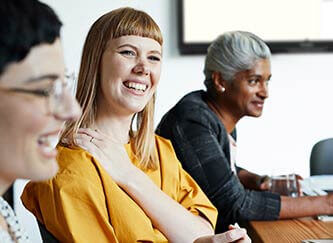 colleagues talking and laughing in a conference room. 