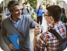 high school teacher shaking hands with student in the hallway