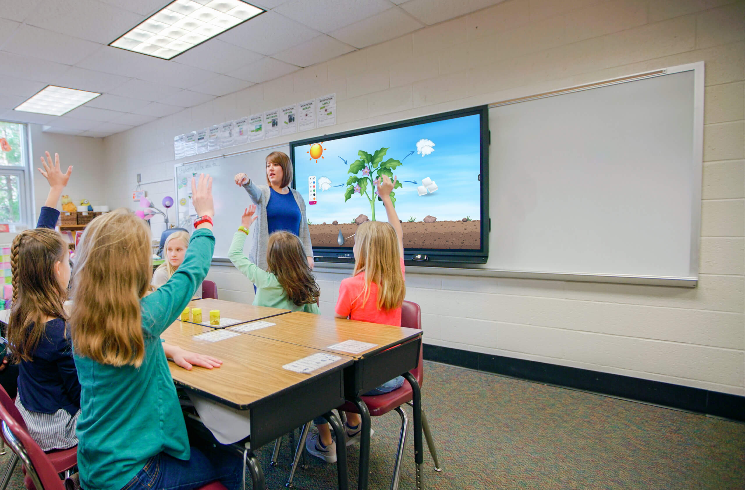 Une classe de jeunes élèves suivent le cours grâce à un écran numérique interactif Promethean.