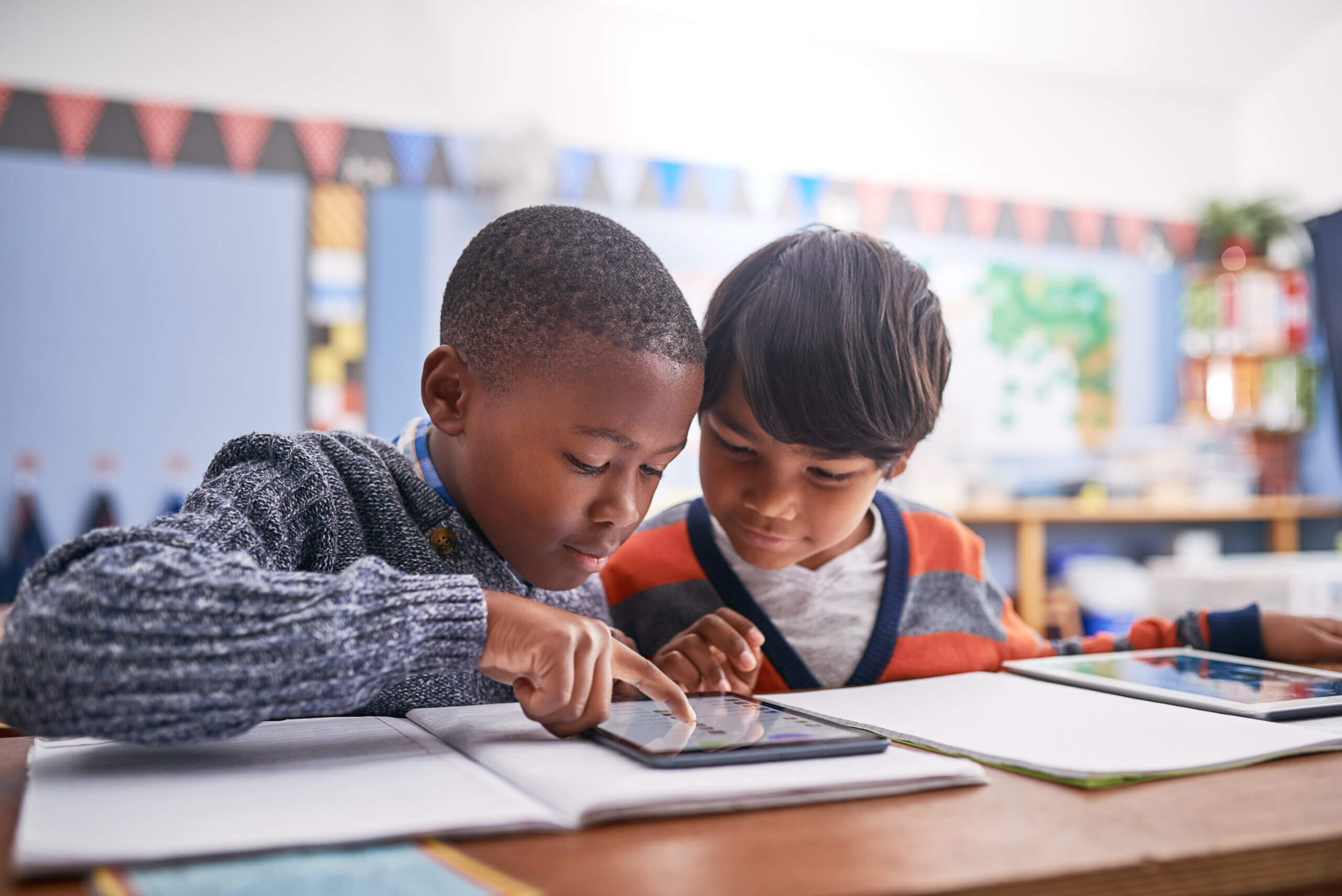 Two primary-age school students work together on an interactive display