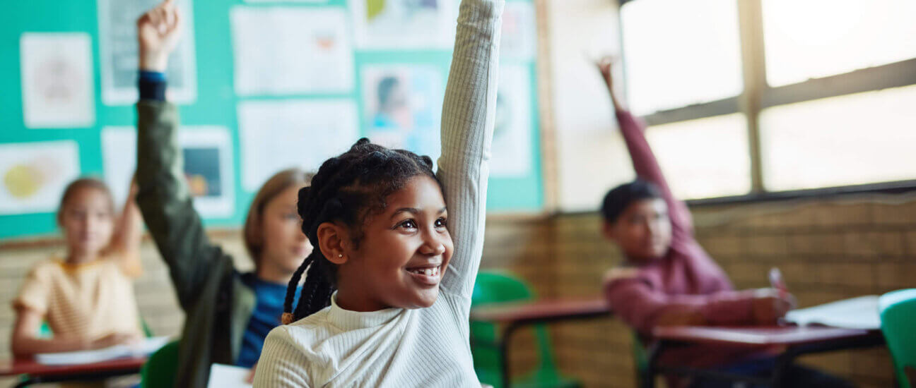 Confident young children raising their hands in a classroom