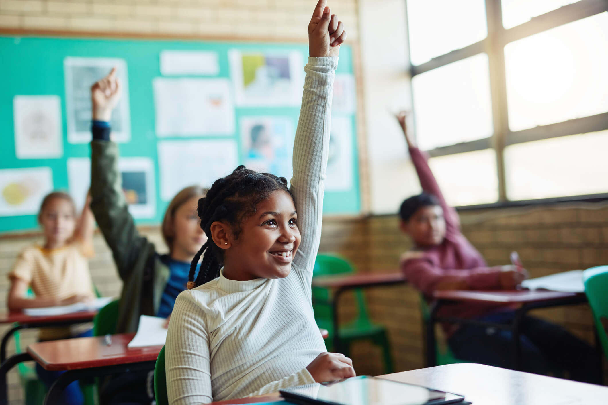Confident young children raising their hands in a classroom