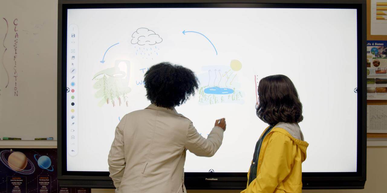 Une professeure et une élève interagissent ensemble pour résoudre un problème sur un écran numérique interactif.