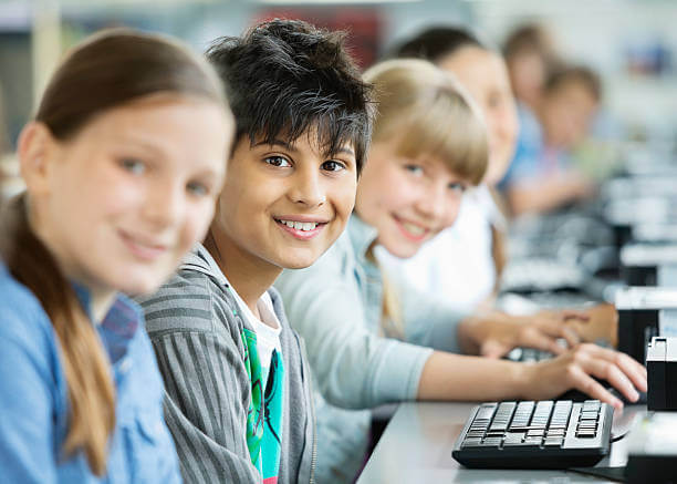 Kinder sitzen an Computern und lächeln digitalpakt 2.0