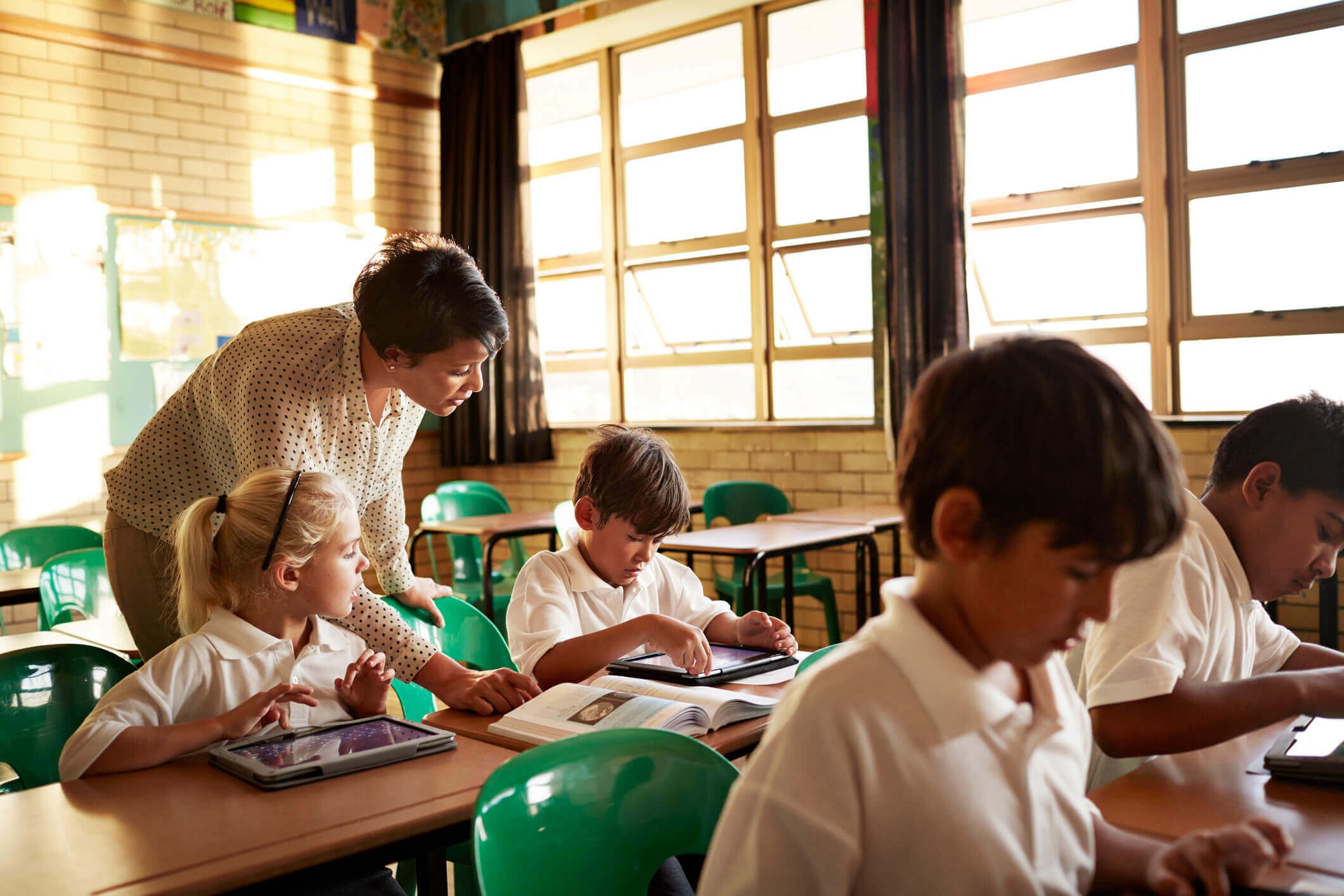 A teacher helping students to learn using digital and paper formats, demonstration inclusion in the classroom
