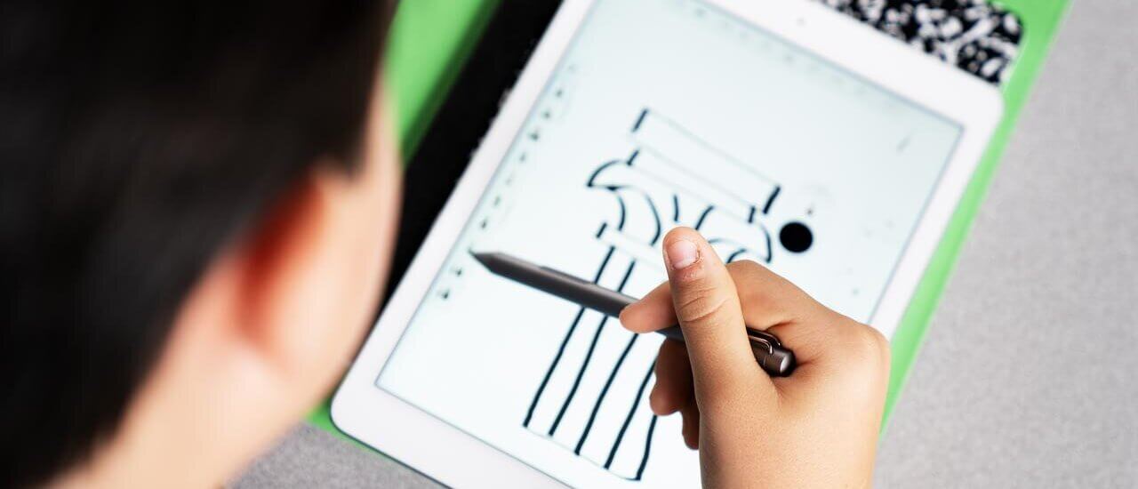 Ein Schüler sitzt an einem Tisch und nutzt ein Tablet in der Grundschule.
