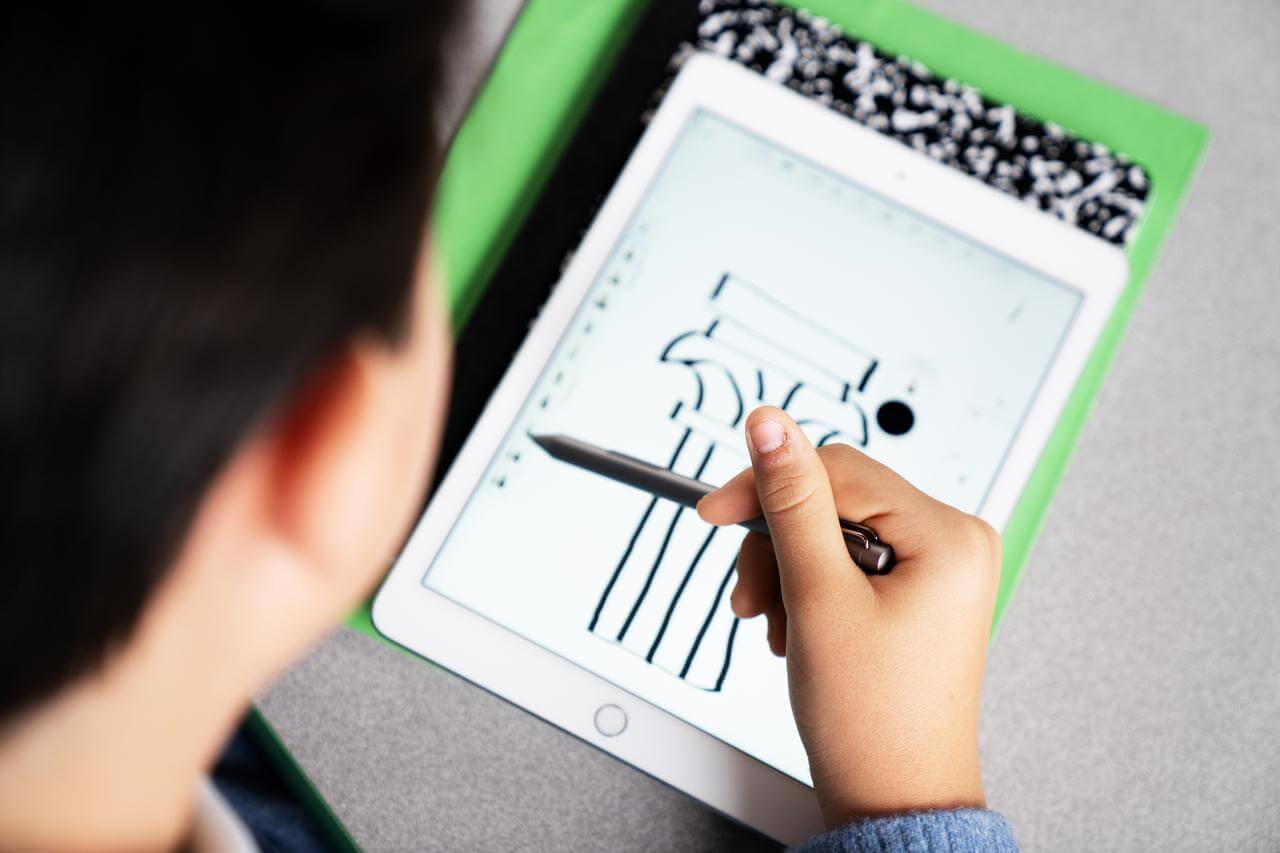 Ein Schüler sitzt an einem Tisch und nutzt ein Tablet in der Grundschule.