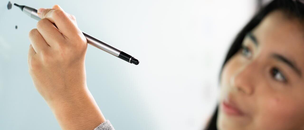 Kind schreibt mit einem digitalen Stift auf einen interaktiven Bildschirm von Promethean.