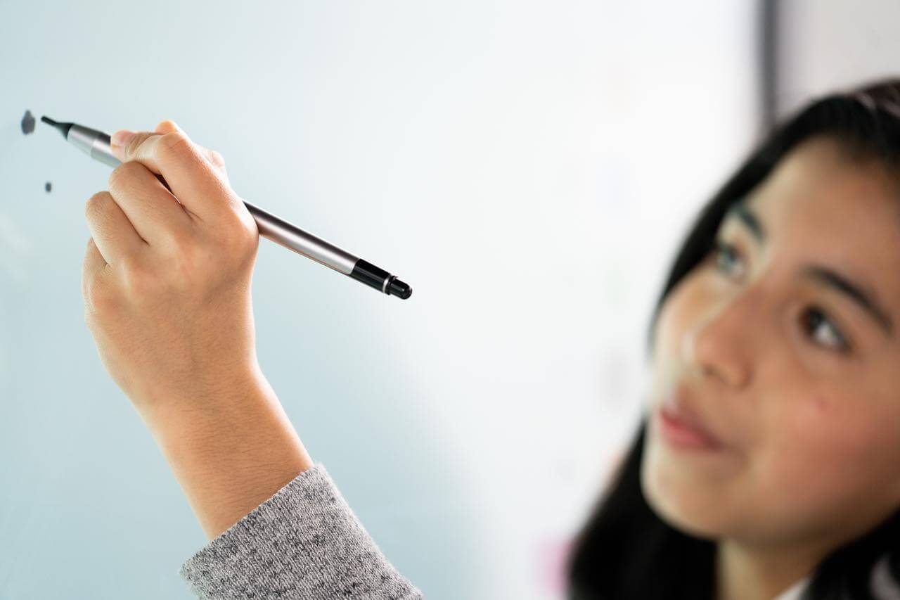 Kind schreibt mit einem digitalen Stift auf einen interaktiven Bildschirm von Promethean.